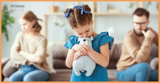 Parents sitting on opposite sides of a couch, sad child in the forefront